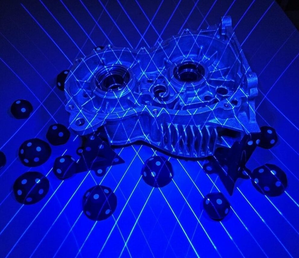 3D-Druck-Dienstleistungen für Industrie und Gewerbe 3 Ein Bauteil wird mit einem Kreuzlinienlaser gescannt. Das Objekt ist dabei in blaues Licht gehüllt.