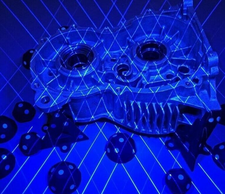 Ein Bauteil wird mit einem Kreuzlinienlaser gescannt. Das Objekt ist dabei in blaues Licht gehüllt.